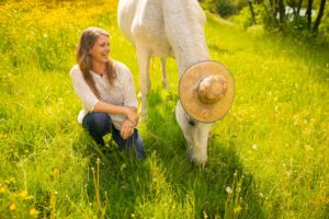 Martina Tömö kniet neben ihrer Stute Bashirah mit Strohhut